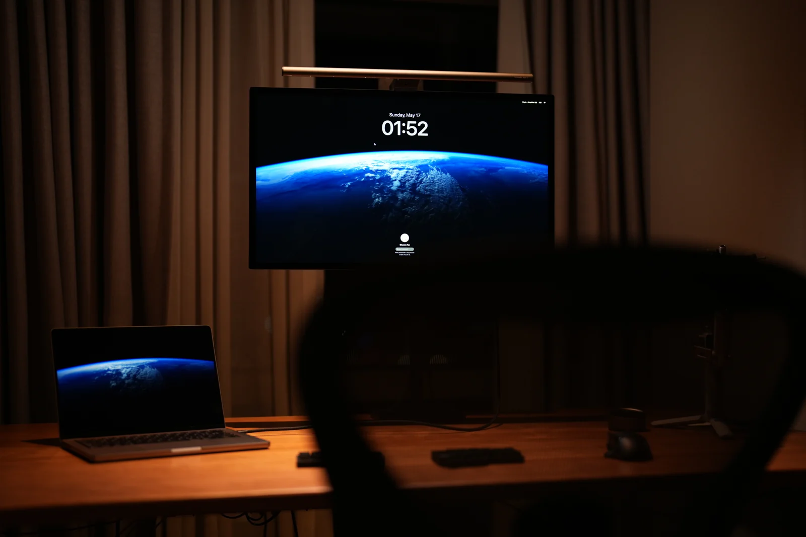 The retouch desk at night, a monitor and laptop under a bar light