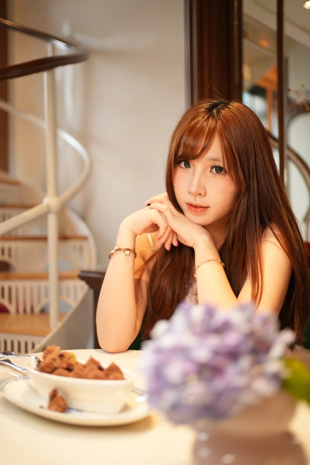 Warm portrait at a cafe table beside a spiral staircase