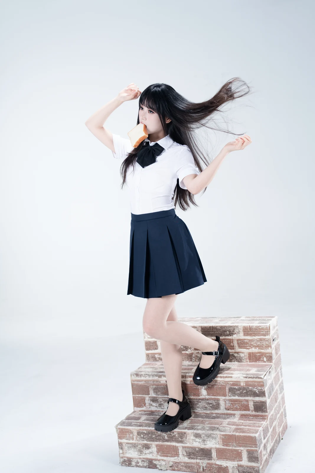 Studio portrait on brick steps, hair caught mid-turn