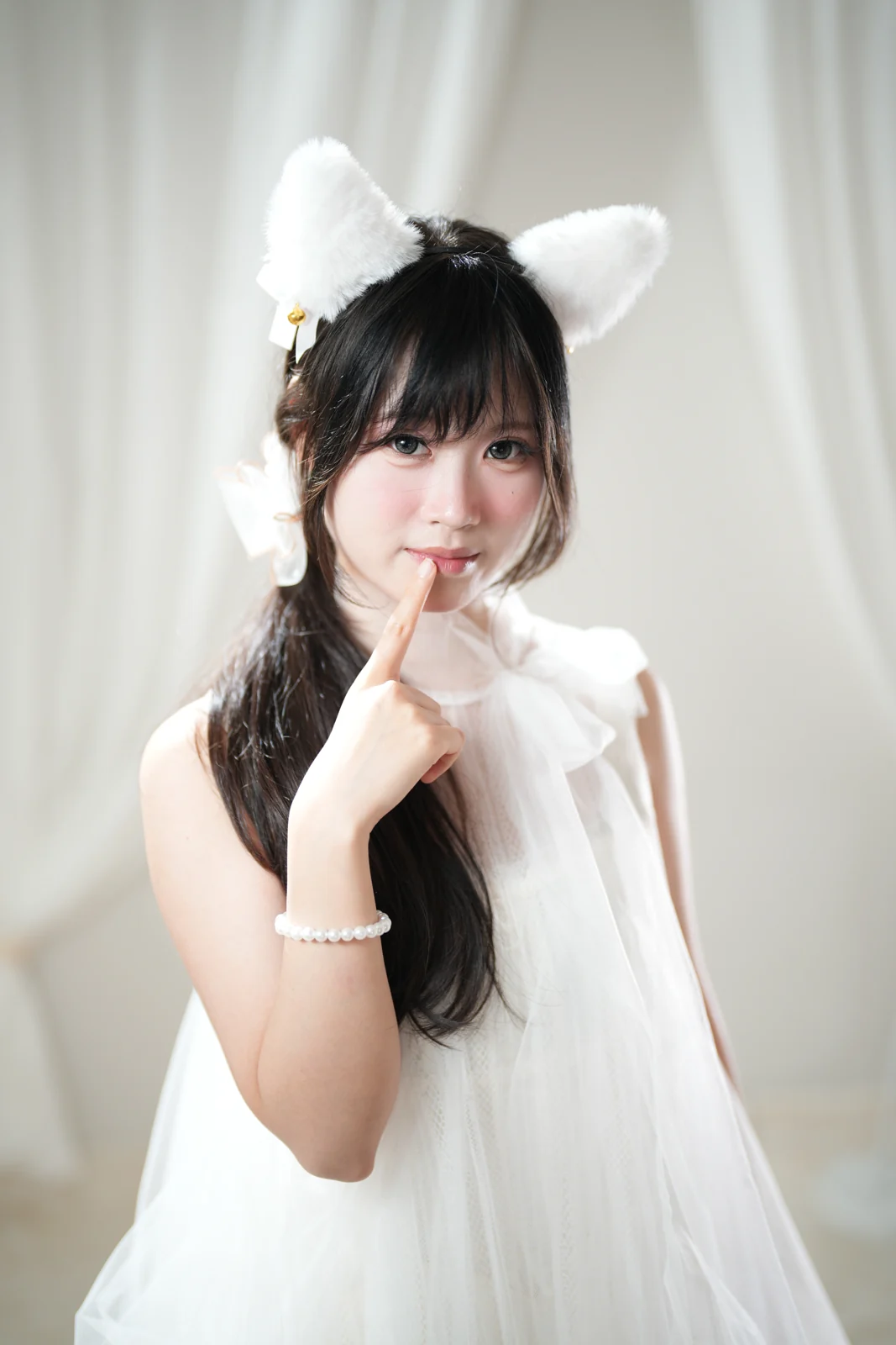 Portrait in a white dress with white cat ears against sheer curtains