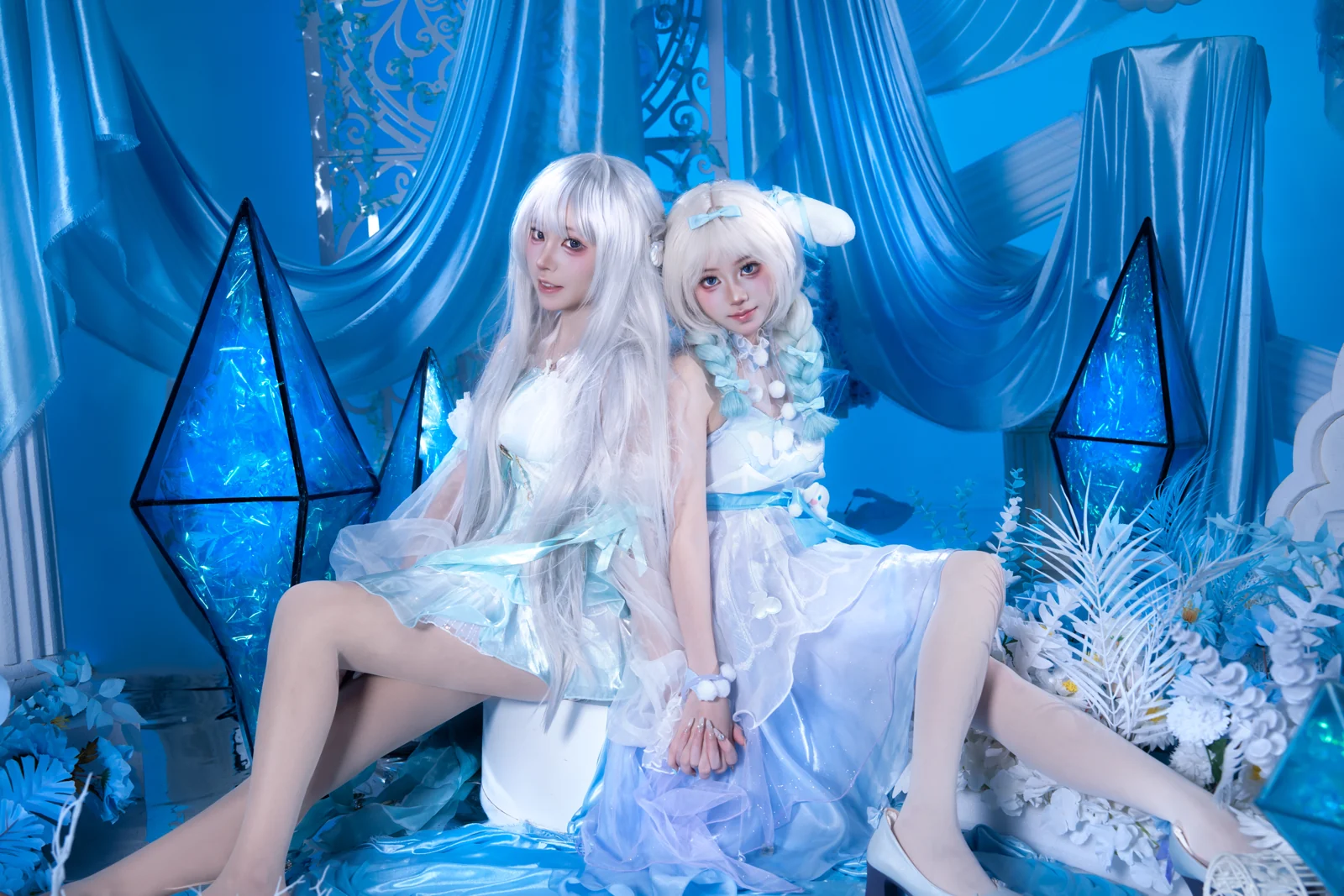 Two figures in white seated between crystal lanterns on an ice-blue set